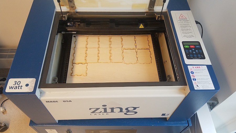 Image of laser-cut plywood sitting an Epilog Zing laser-cutter after cutting finished.
